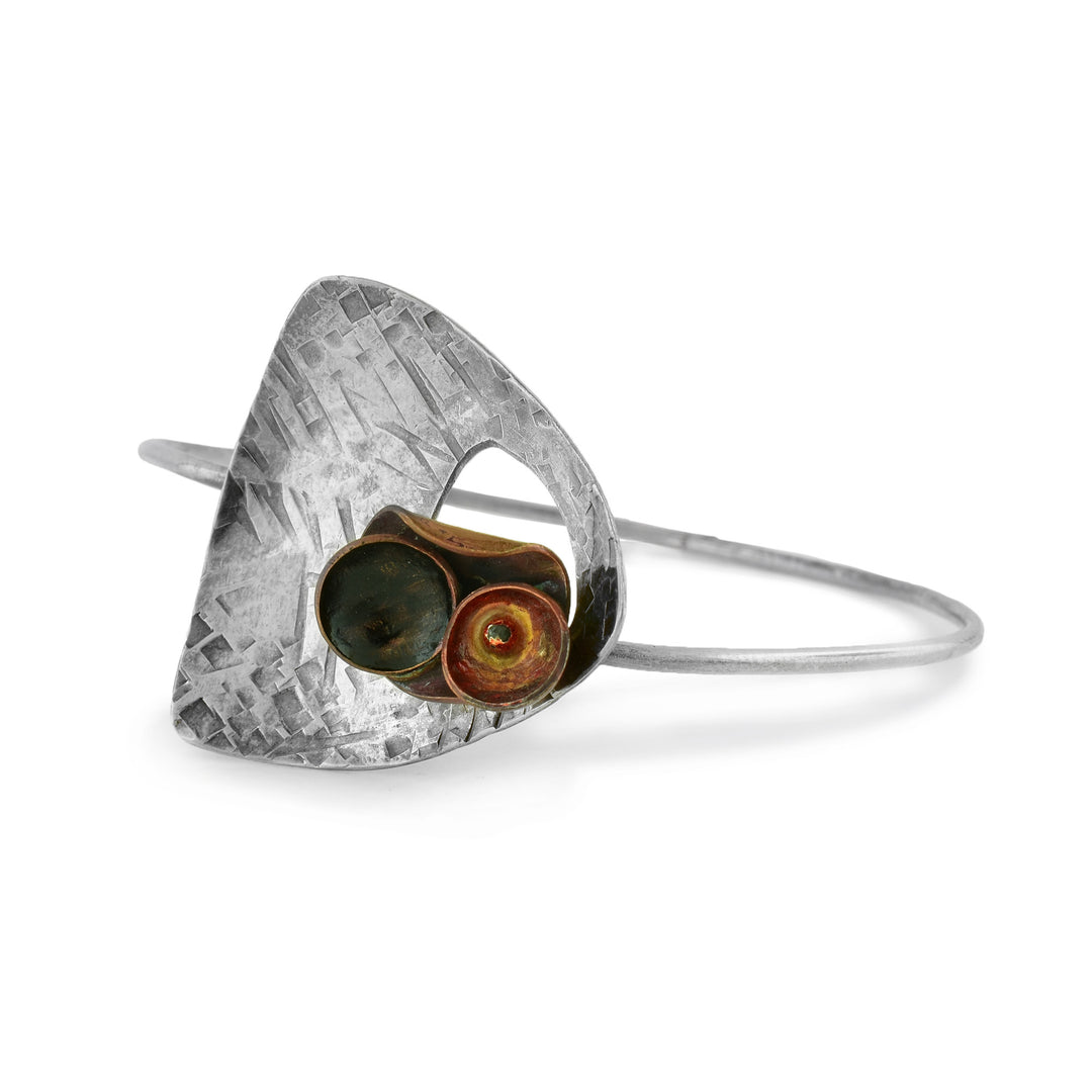 A sterling silver bangle bracelet has a large top and smaller copper designs to make for a form of corsage. 