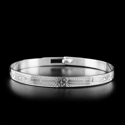 A sterling silver bangle bracelet that depicts two Hummingbird faces facing eachother with a flower in between them. The bodies of the Hummingbirds are engraved on the rest of the bracelet.