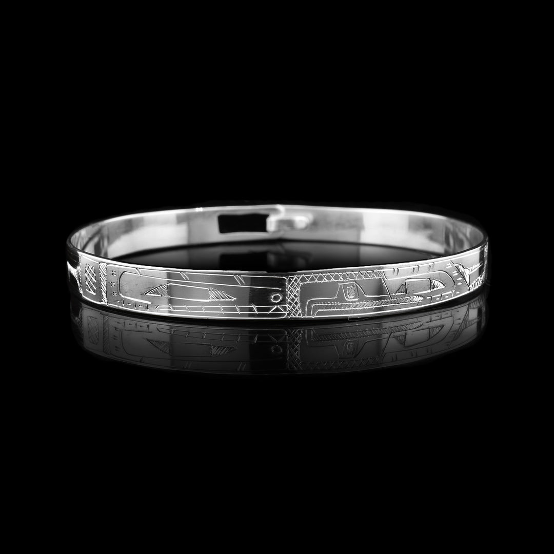 This Eagle and Orca bracelet bangle features a thin band crafted from sterling silver and secured with a clasp at the back. The legendary animals are intricately carved in side profile along the band, with their faces meeting at the center of the piece in a powerful display of unity and balance.