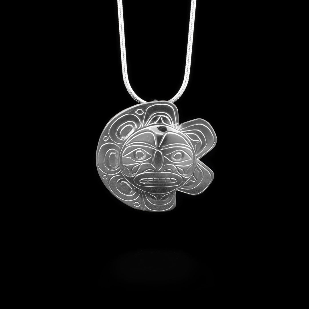 This eclipse Moon and Sun pendant is made from sterling silver and circle shaped. Each half of the pendant has carvings that depict the Sun and the Moon in eclipse.