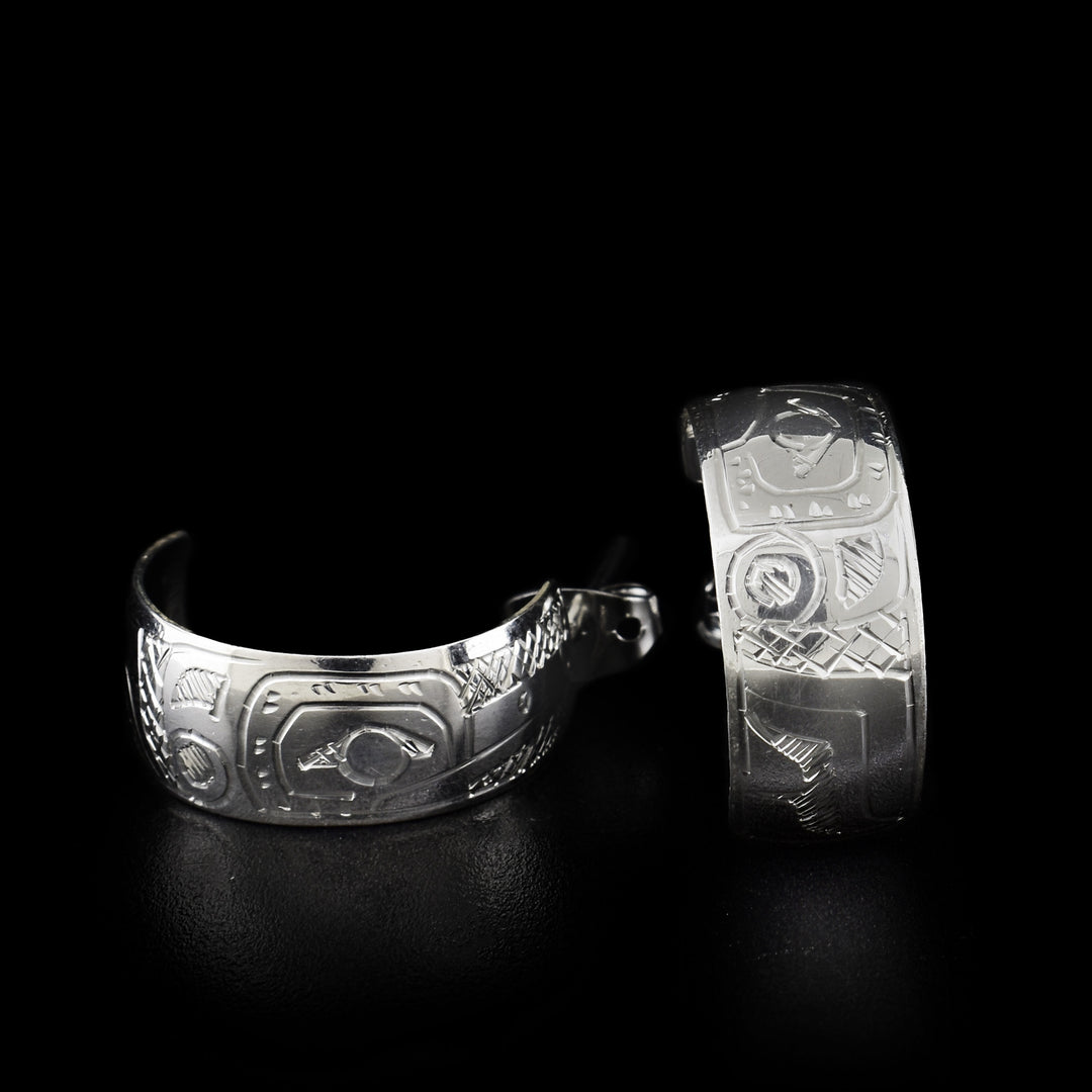 These wide hoop earrings are made out of sterling silver. The earrings have a carved face of the Hummingbird on them.