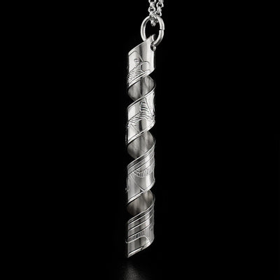 This pendant is made out of a sterling silver strip which has the face and body of the Raven carved on it and then coiled into a spiral.