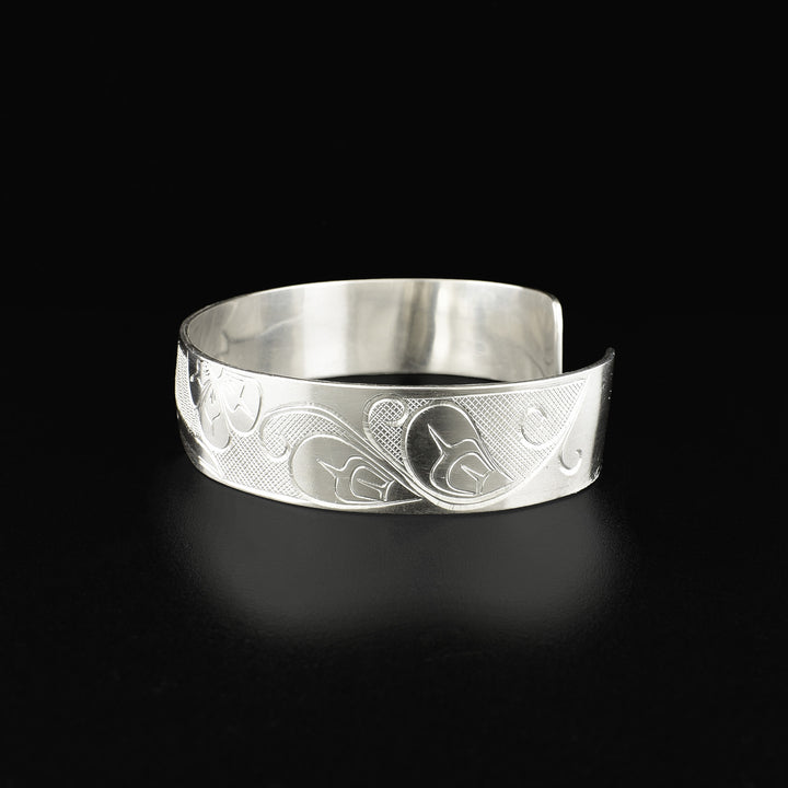 Right side of cuff bracelet depicting flower and petal-like shapes. Background is cross-hatching.