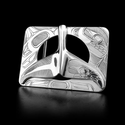 This sterling silver belt buckle is shaped like a rectangle and has a whale tail on it. The space between the whale tail and the ractangle is cut out. The face of the Orca is engraved on one side of the whale tail and in the corner of the rectangle.