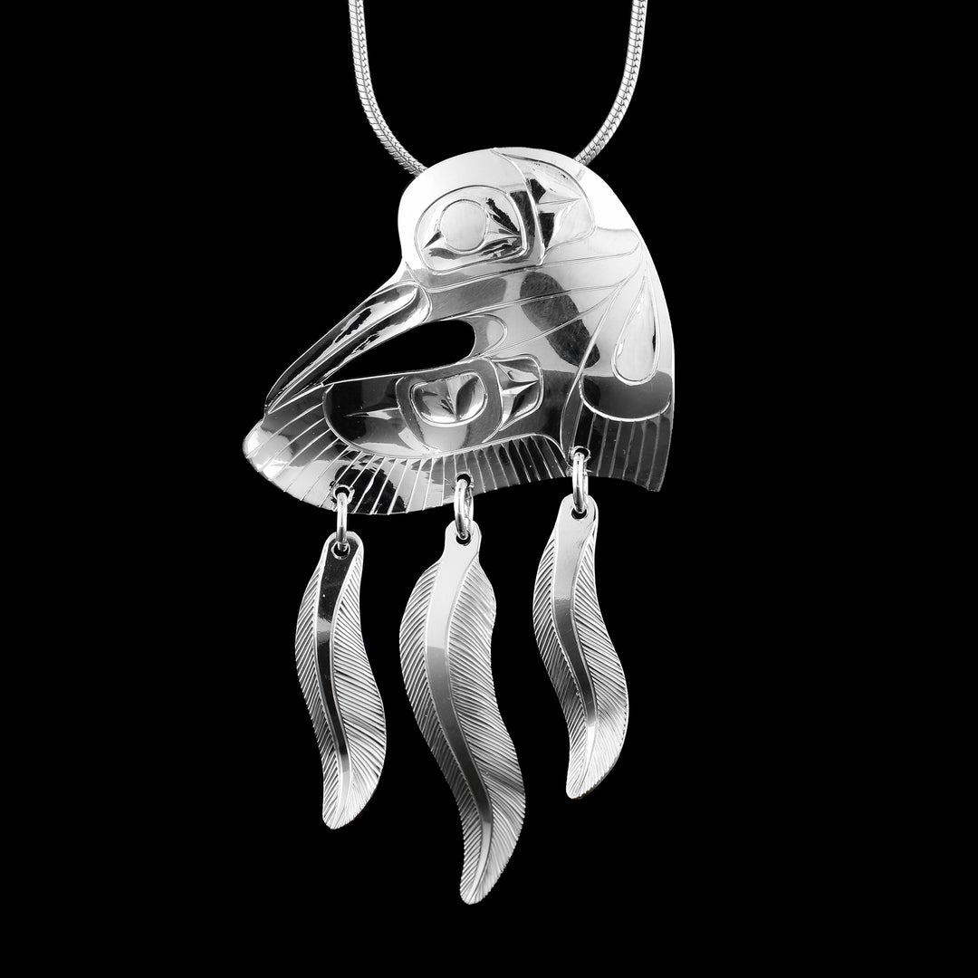 Sterling silver hummingbird feather dangle pendant by artist Fred Myra, featuring detailed carving of a hummingbird in flight in the shape of a heart and three dangling feathers.