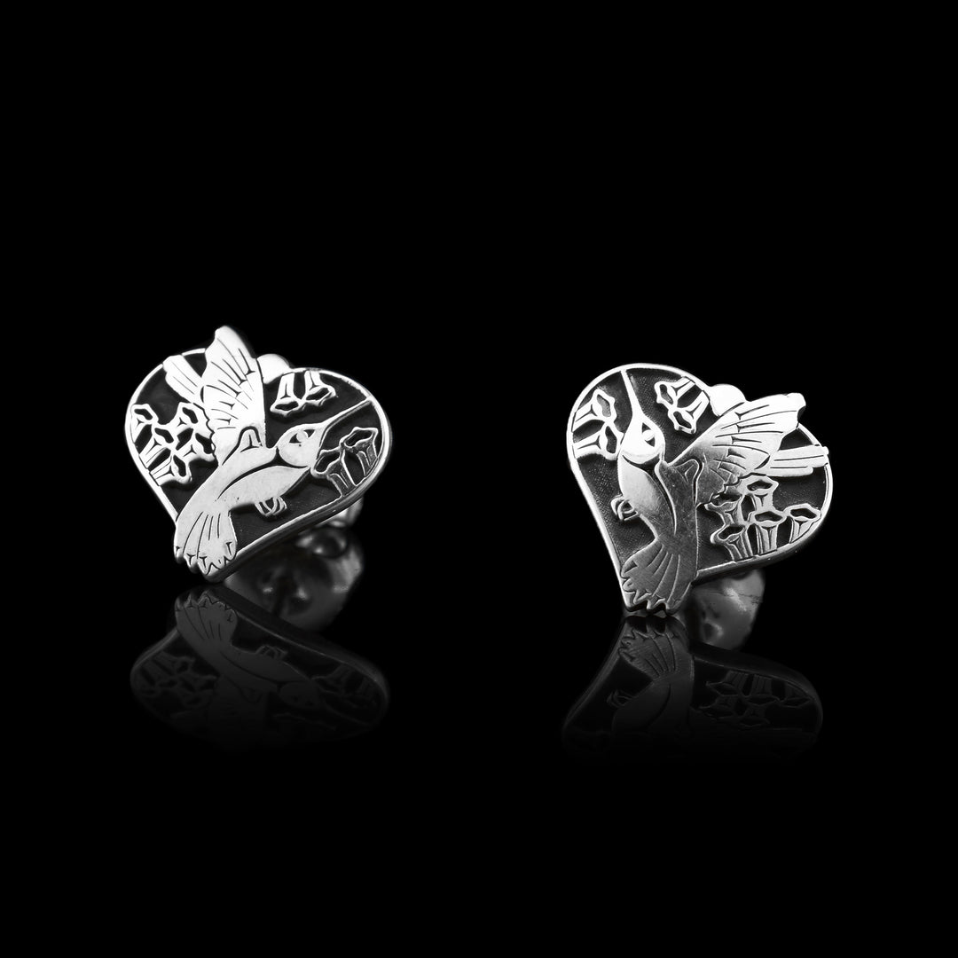 Sterling Silver Hummingbird Heart Shaped Studs. These earrings have hummingbirds flying through hears with flowers in the background. A detailed piece of jewellery.