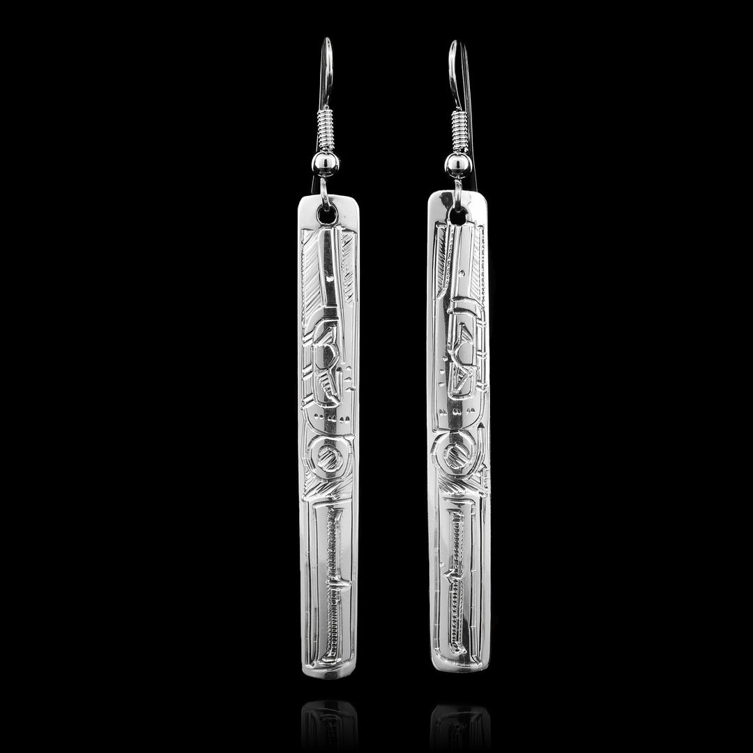 These sterling silver dangle earrings have long, thin, rectangular hangs with depictions of the Hummingbird carved into them.