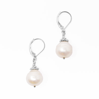 Lever-back earrings with round, uneven freshwater pearls. Pearls are framed by adornments on top. Each earring measures 1.38” x 0.44” including hook.
