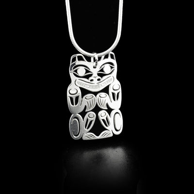 Sitting bear, front view. Front paws and back paws together. Teeth showing. Pierced design. By Tahltan artist Grant Pauls.