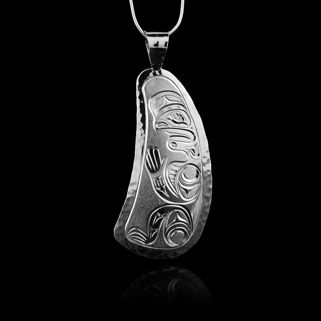 This sterling silver mussel human pendant. The shape of the pendant is the shape of a mussels with a hand carved depiction of a human on the surface of the shell.