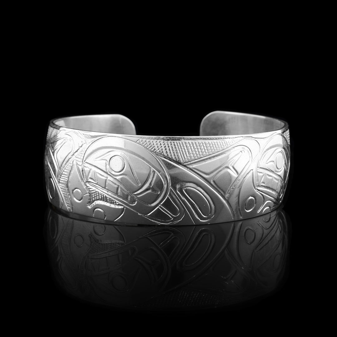Sterling Silver bracelet that is styled into a cuff, engraved in the cuff is a pod of orcas.