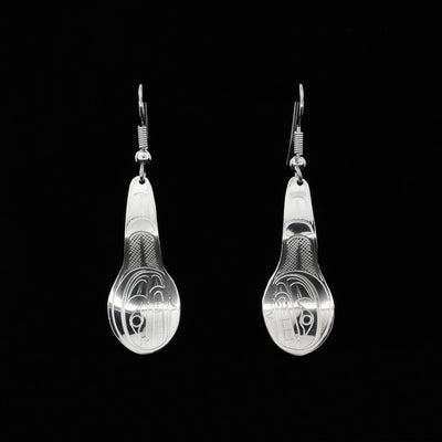 Dangle earrings hand-carved by Coast Salish artist Travis Henry. Each earring depicts the side-view of an orca's head and fin on the spoon. Each earring measures 2” x 0.6” including hook.