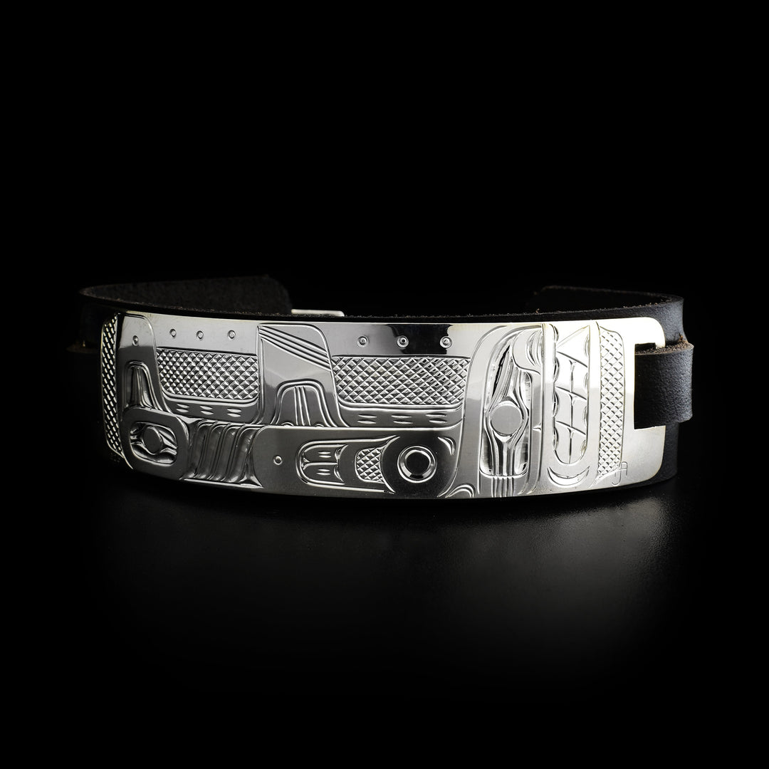 Leather cuff has sterling silver plate with side-view of orca. Design is done in ovoids, lines and cross-hatching. Leather is black.