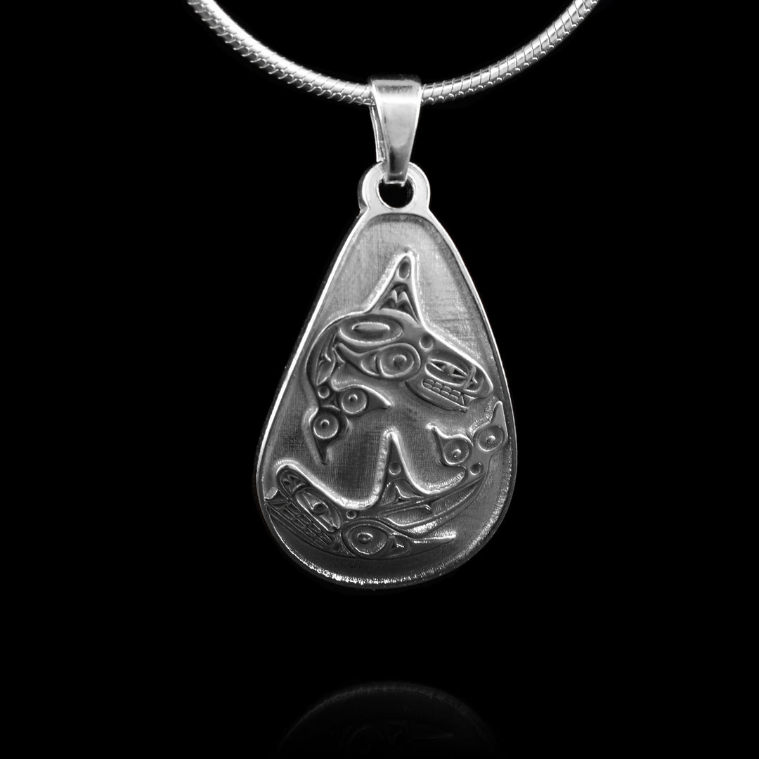 This striking teardrop pendant is crafted from sterling silver and features a wide, rounded teardrop shape. One half of the pendant showcases a full-bodied Orca captured in mid-leap, while beneath it, an orca swims underneath it.
