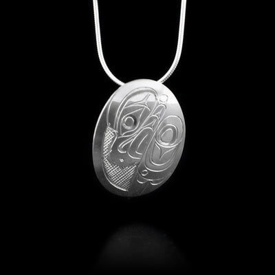 Domed sterling silver oval pendant featuring side-view of eagle. Cross-hatching background. Hidden bail on back. By Kwakwaka’wakw artist Don Lancaster.