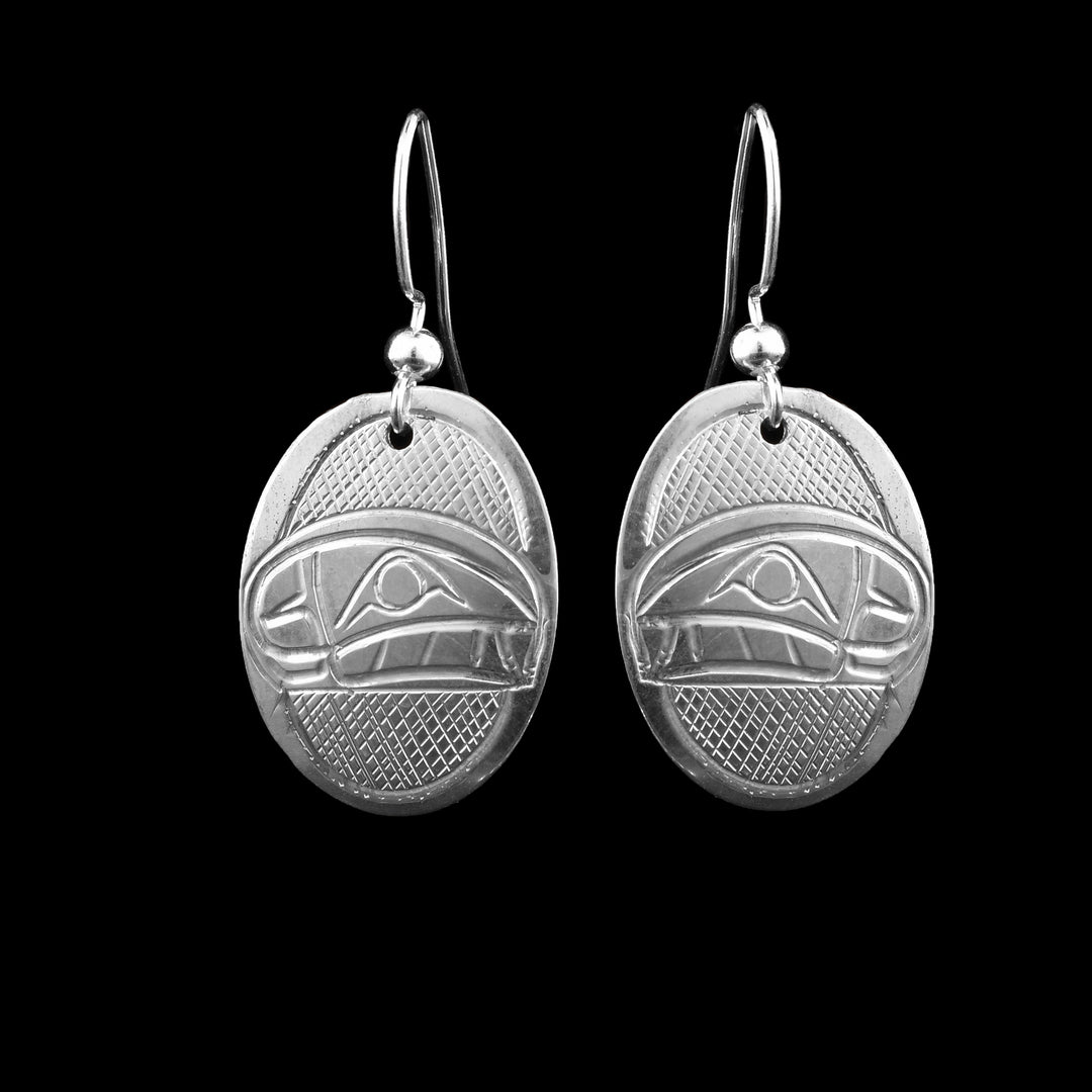 These sterling silver oval orca dangle earrings have been carved with the legend of the orca. There face in the middle of the earring and the background in a cross hatch pattern.