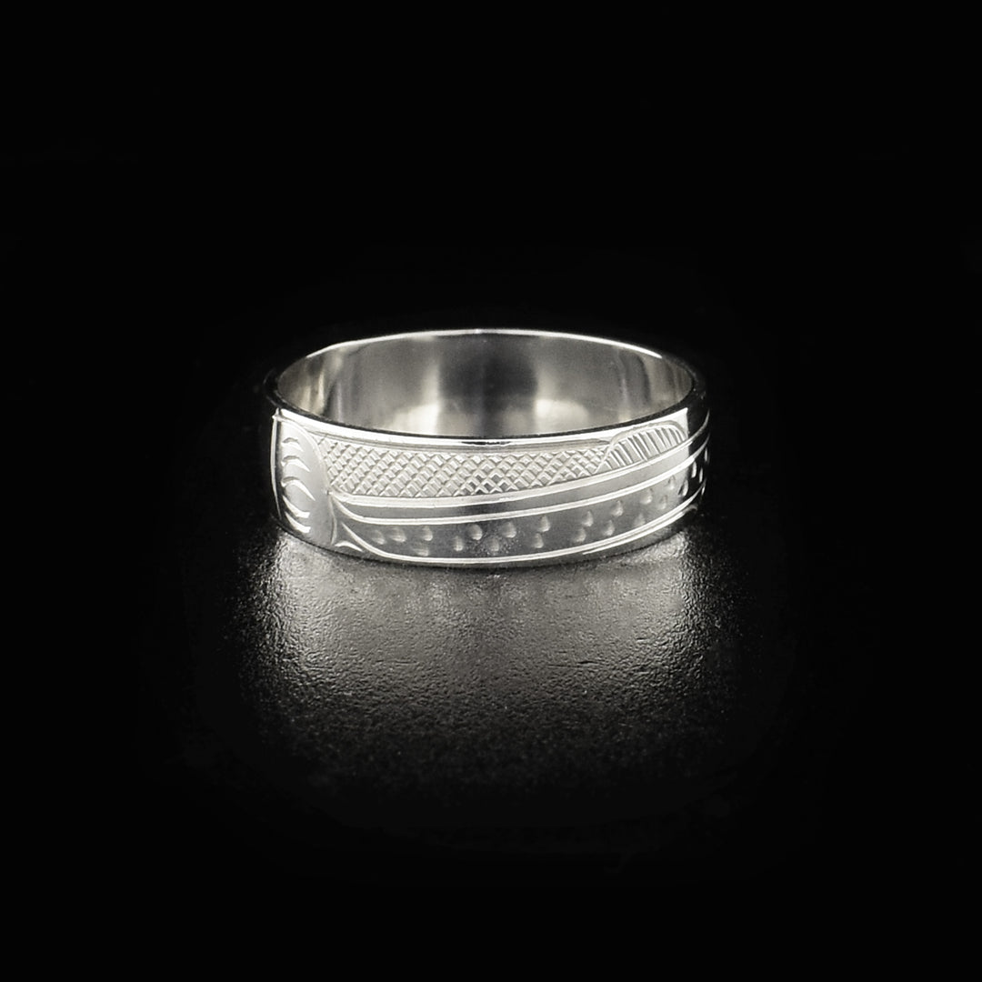 This sterling silver band ring has a single, sterling silver band with a depiction of the Salmon carved into it. The legends full body is shown at a side profile and there are cross hatching design in the background of the piece.
