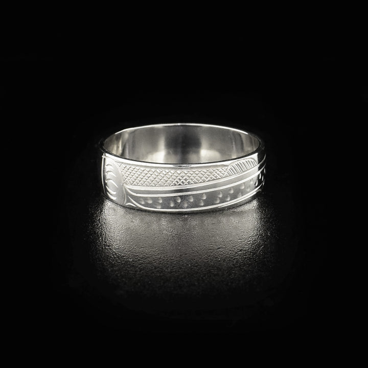 This sterling silver band ring has a single, sterling silver band with a depiction of the Salmon carved into it. The legends full body is shown at a side profile and there are cross hatching design in the background of the piece.