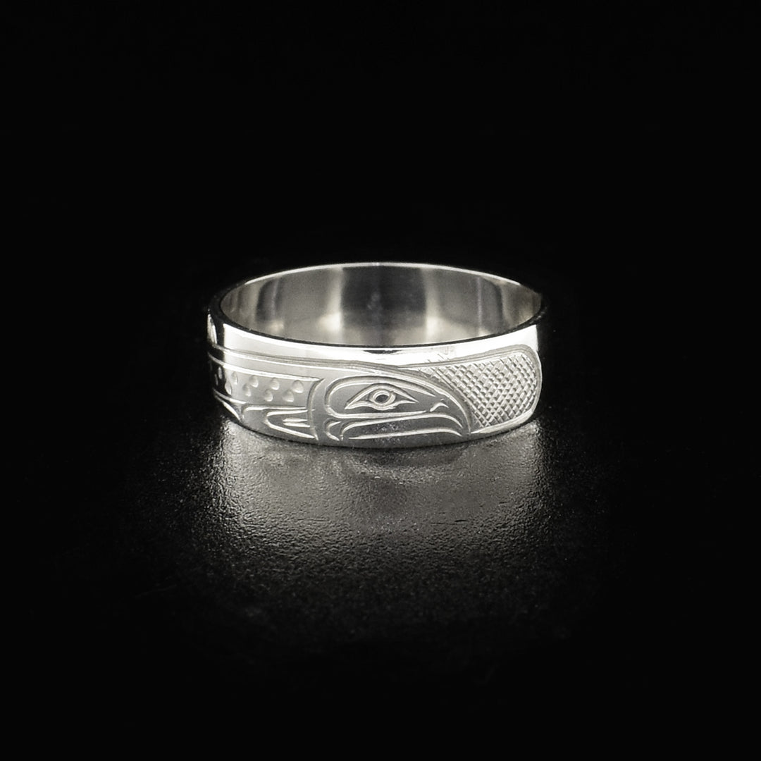This sterling silver band ring has a single, sterling silver band with a depiction of the Salmon carved into it. The legends full body is shown at a side profile and there are cross hatching design in the background of the piece.