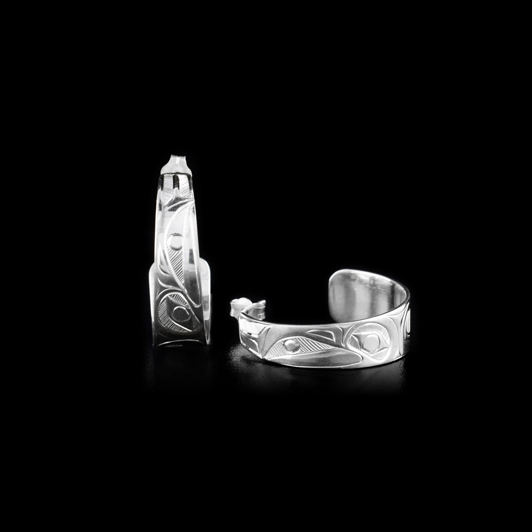 The Sterling Silver Raven Half Hoop Earrings are hand carved by artist, Hollie Bartlett. These bands curve backwards and are tapered slightly. The head of the Raven is depicted in a side profile with a pearl in its mouth.