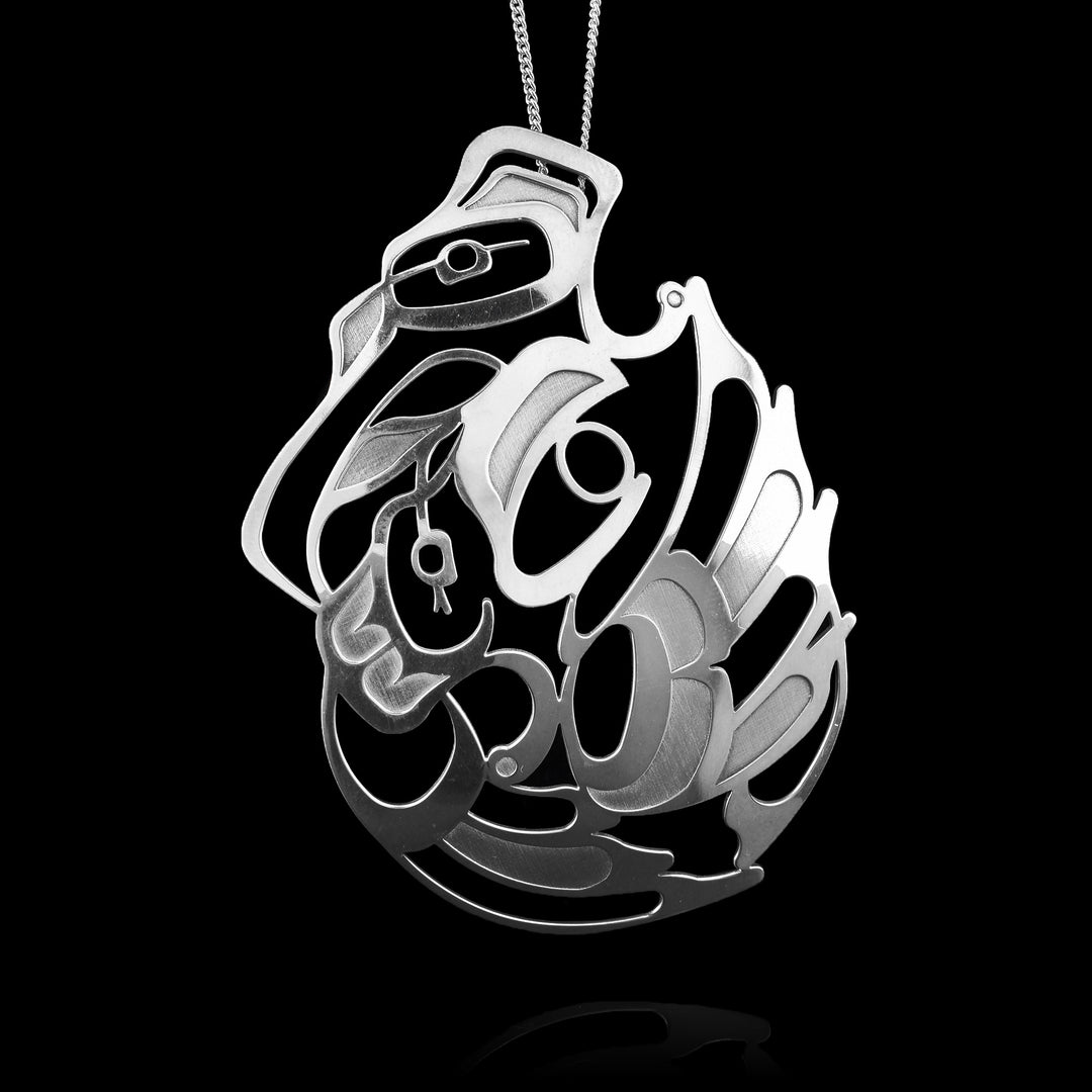 This handcrafted sterling silver Raven pendant by Haida Gwaii artist Gina Mae Schubert. This unique piece features a detailed carving of a mother and child Raven in a symbolic embrace.