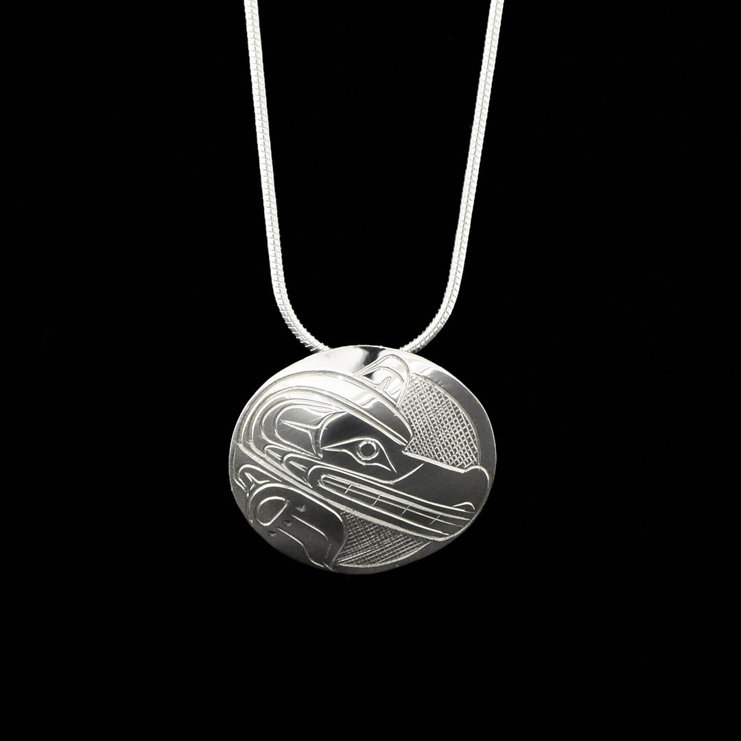 Domed pendant featuring side-view of a wolf’s paw and face, mouth is open showing teeth. Wolf design done in ovoids and lines, background is cross-hatching. 1” diameter. Hidden bail on back.