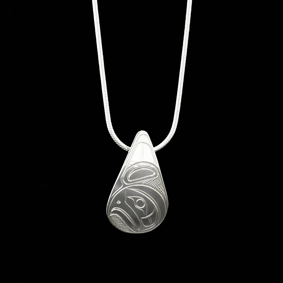 Domed pendant featuring side-view of an eagle’s wing and face, beak is closed. Eagle design made of ovoids and lines, background is cross-hatching. Measures 1” x 0.63”. Hidden bail on back.