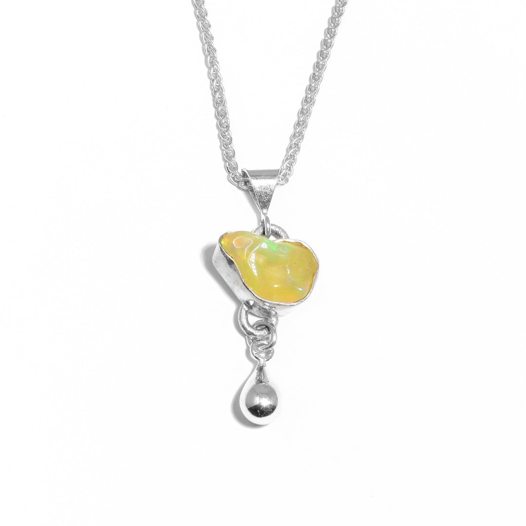 Natural-shaped, polished, yellow Ethiopian opal set in silver with silver teardrop adornment below. Metal is sterling silver.