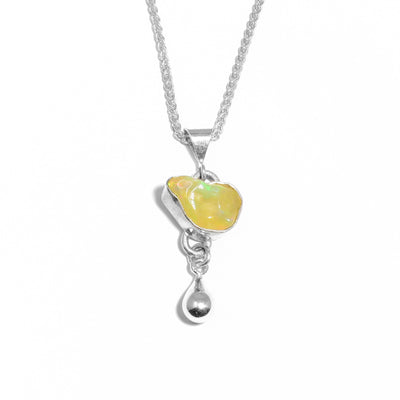 Natural-shaped, polished, yellow Ethiopian opal set in silver with silver teardrop adornment below. Metal is sterling silver.