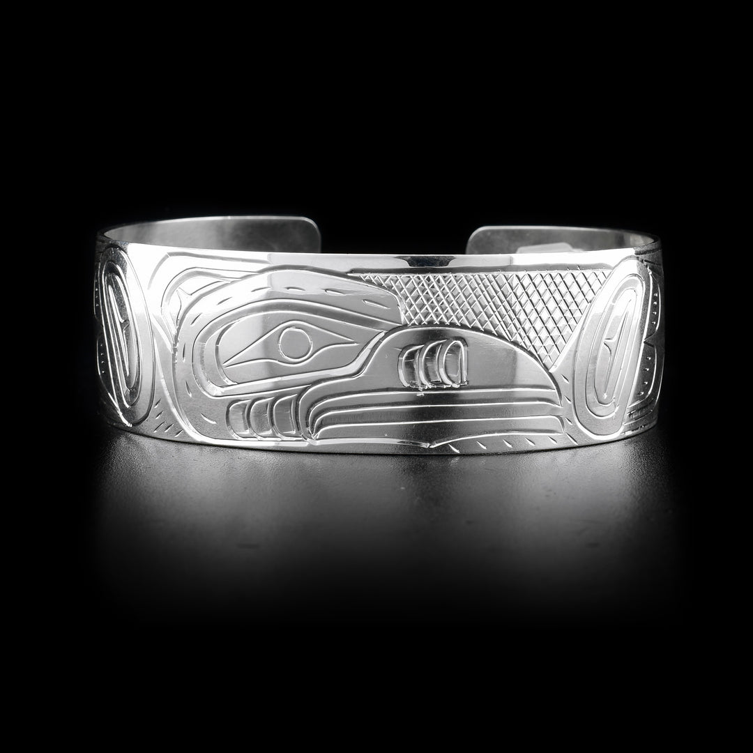 This wide cuff bracelet has a wide, sterling silver band with a gap in the back. There is a depiction of the Hummingbird carved into the surface of the band.