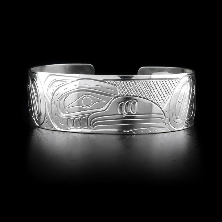 This wide cuff bracelet has a wide, sterling silver band with a gap in the back. There is a depiction of the Hummingbird carved into the surface of the band.