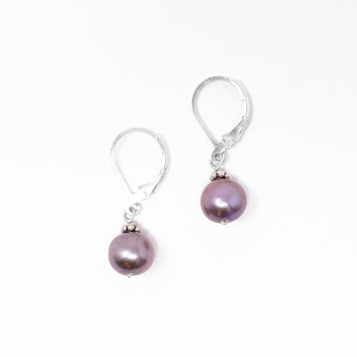 Lever-back earrings with round freshwater pearls. Pearls are framed by oxidized silver adornments on top. Each earring measures 1.13” x 0.31” including hook.