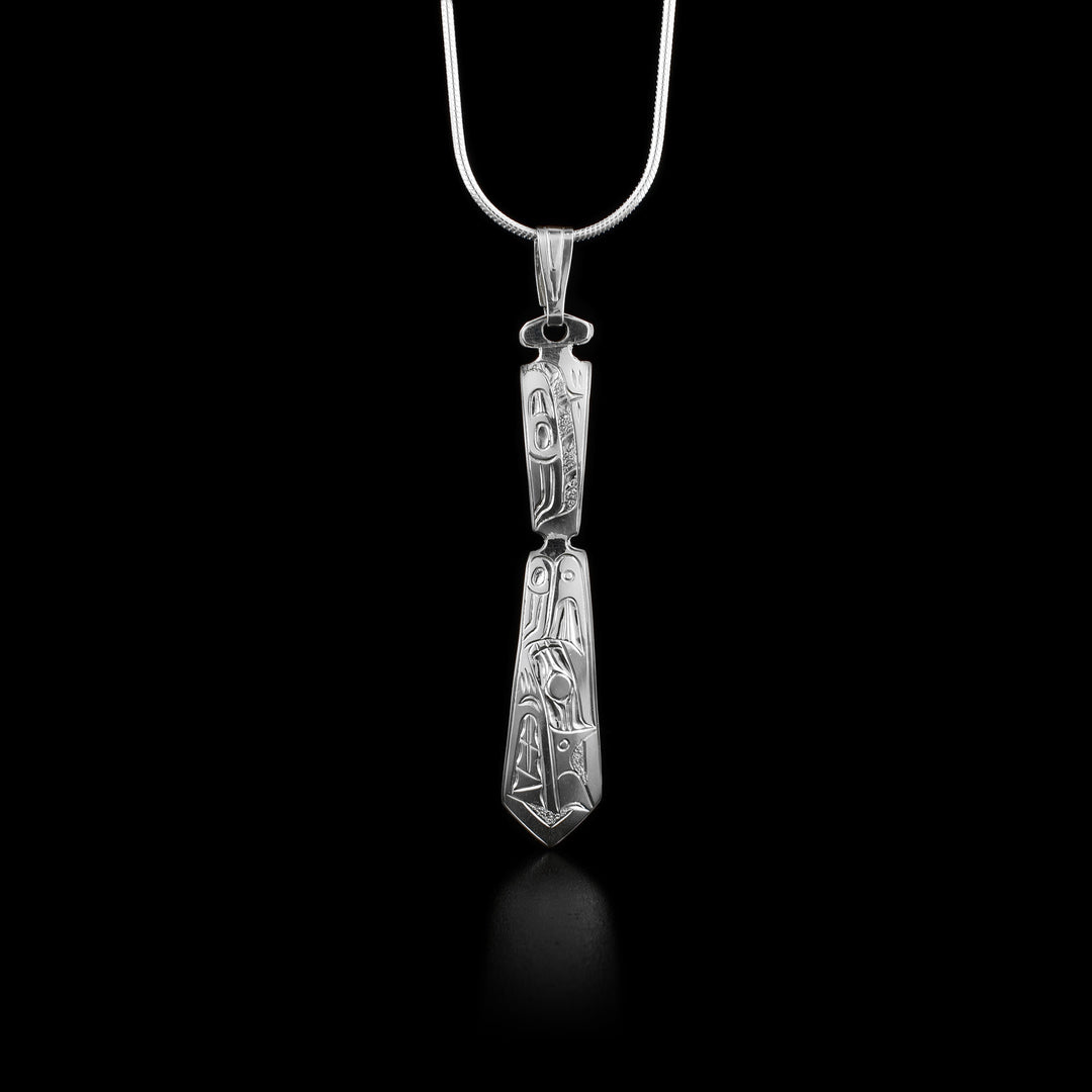 Pendant in shape of west coast Indigenous paddle. Design on paddle is side view of wolf facing downwards. Wolf has teeth showing and is done in lines and ovoids.