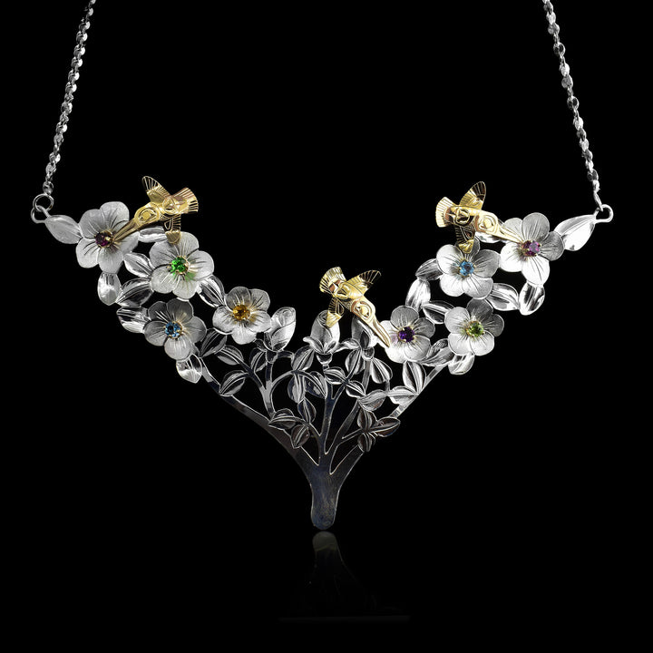 Sterling Silver and 14k Gold Hummingbirds Garden of Gems Necklace. A garden of sterling silver flowers and in the middle of the flowers are set gemstones of different colours citrine, blue topaz, tsavorite, rhodolite garnet, peridot and amethyst. Above the flowers fly 3 hummingbirds that are plated in 14k gold.