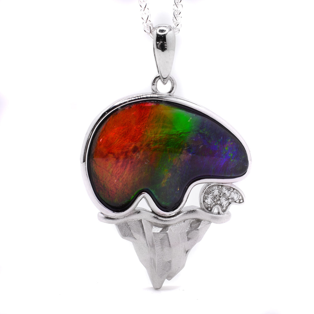 This sterling silver pendant depicts an ammolite bear as well as a small cub standing on a mountain.