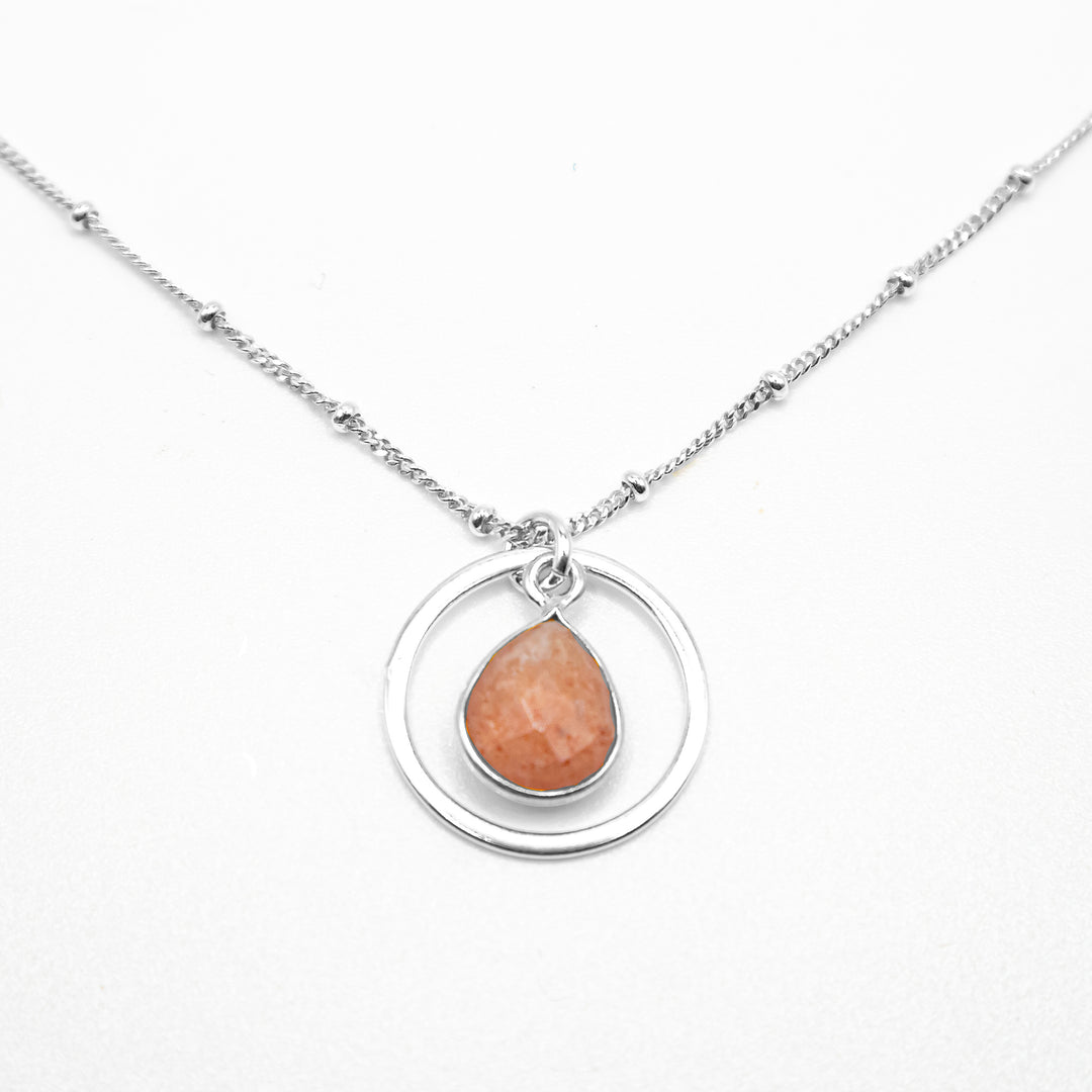 Pendant necklace with flat, faceted strawberry quartz teardrop dangling in hoop. Satellite chain included. All metal is sterling silver.