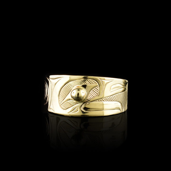 This Eagle gold ring has a wide band made from 14K gold and tapers in the back. The head of the eagle is beautifully carved at a side profile and its beak is open. There is a gold stud that is place in the eye and there are cross hatching designs in the background of the scene.
