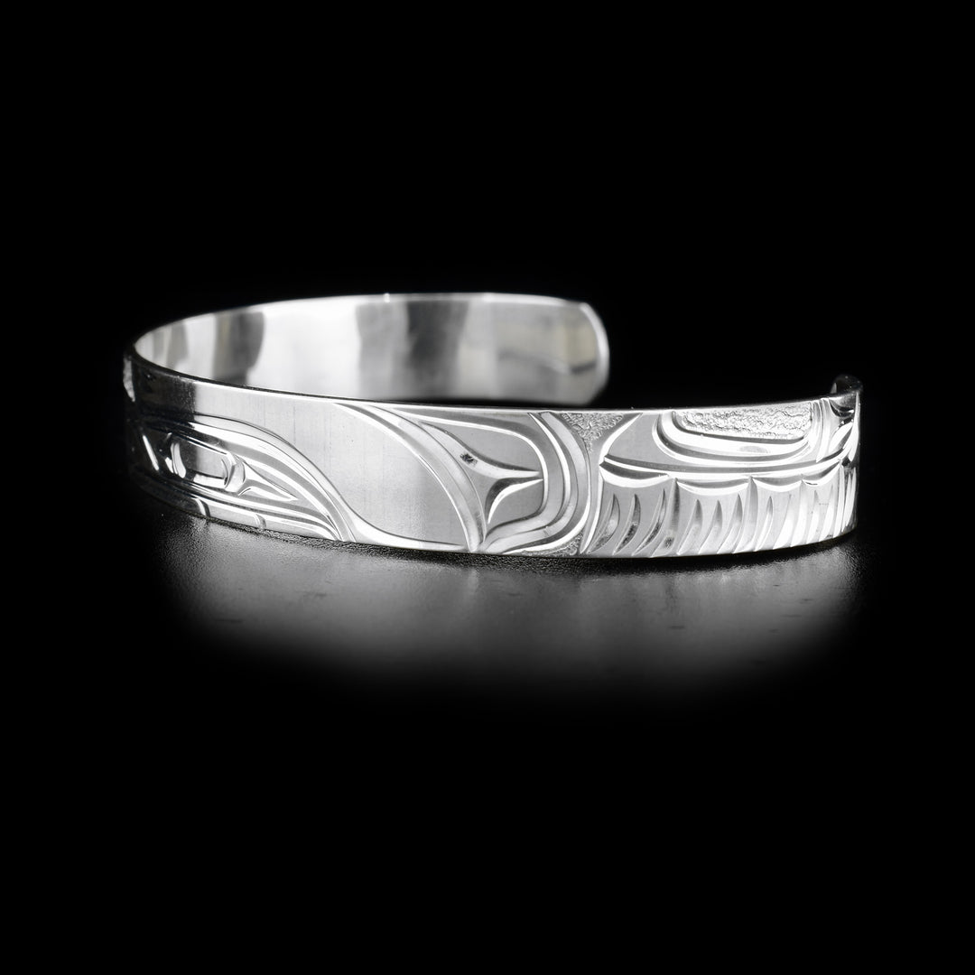 Left side of bracelet with carved design and textured background.