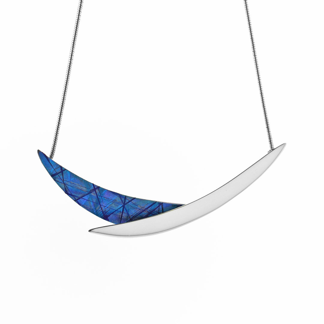 This silver and titanium necklace is made from sterling silver and anodized titaniumthe pendant is made of an anodized titanium piece and a silver piece that are connected to form a cradle shape.