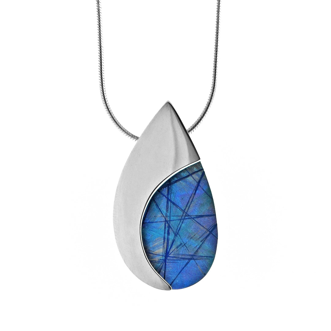 This elegant teardrop pendant necklace is made from sterling silver and anodized titanium. Half the pendant is made from silver and the other half is light blue with colorful designs achieved by anodizing the metal.