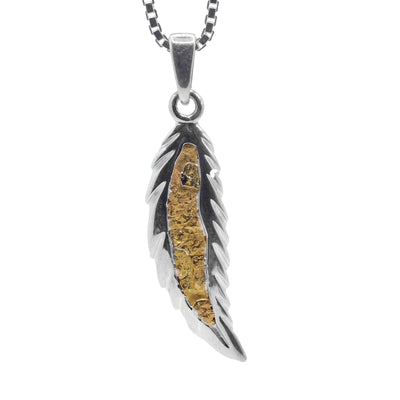 This gold feather pendant is made from sterling silver and is feather shaped. There are carvings made around the piece giving texture and a featherlike appearance to it. In the middle of the pendant there are 22K gold nuggets.