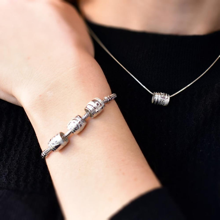 Photo showing charm beads worn on a chain and a bracelet.