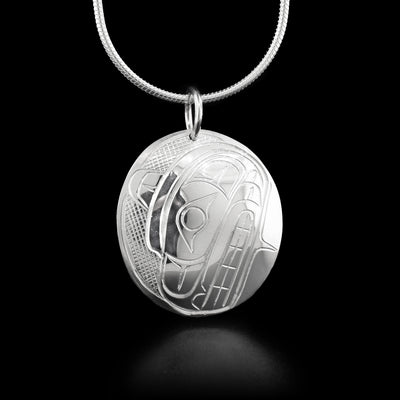 A sterling Silver Pendant handcarved by Coast Salish artist Travis Henry. The oval pendant depicts the face of the Bear.
