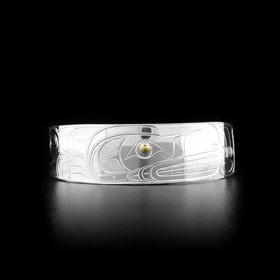 This Wolf bracelet cuff is made from sterling silver and 14K gold and has a wide band with a gap in the back. There are depictions of the Wolf carved into the surface of the band and the eyes of the Wolf are made from gold..