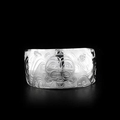 This unique Orca, Sun, and Eagle bracelet is made from sterling silver and has a wide band. There is a depiction of the Sun carved into the center of the band and there are depictions of the Eagle and the Orca carved to either side of the Sun.