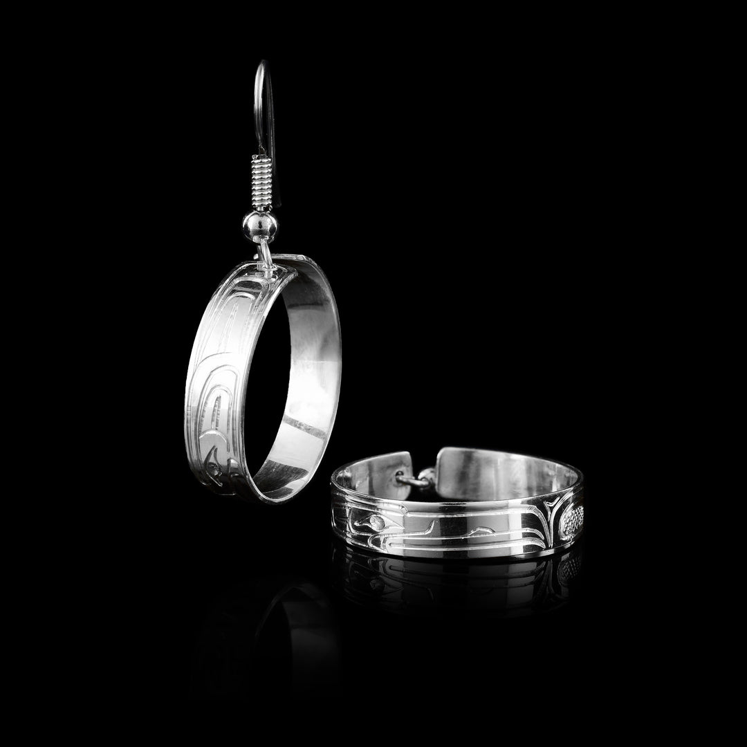 Handcrafted by Coast Salish artist Travis Henry, these sterling silver dangle hoop earrings feature the legendary Raven, creatively hand-carved in a modern style.