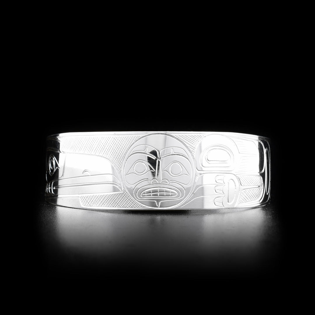 This Raven and Moon bracelet cuff is made from sterling silver and has a wide band with a gap in the back. There are depictions of the Raven and the Moon carved into the surface of the band.