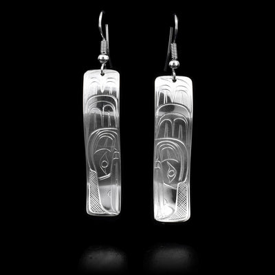 These sterling silver dangle earrings have rectangle shaped hangs with depictions of the Raven carved into the surface of them.