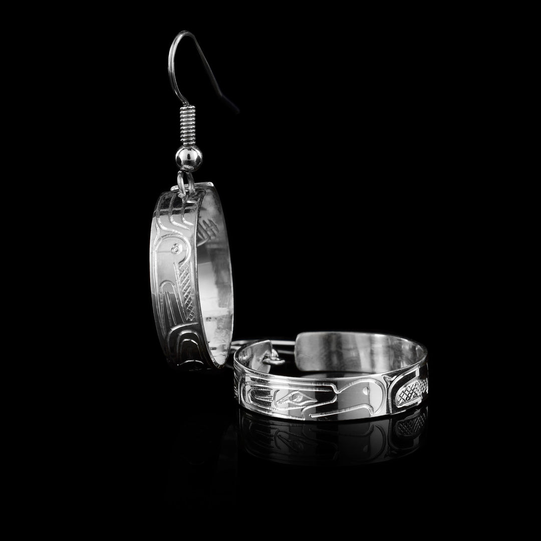 These Thunderbird hoop dangle earrings are handcrafted by Coast Salish artist Travis Henry and available at Artinas. Featuring the powerful Thunderbird—a symbol of protection and strength—the legend is creatively hand-carved into high-quality sterling silver. A perfect blend of traditional storytelling and contemporary style.