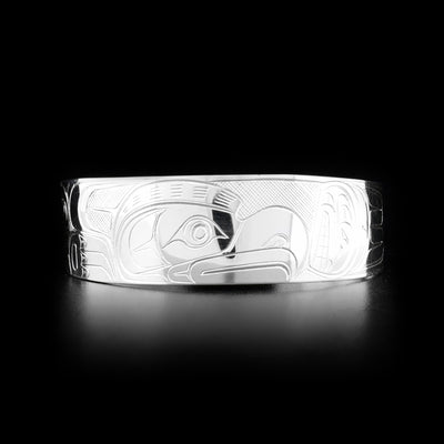 This Orca and Thunderbird bracelet cuff is made from sterling silver and has a wide band with a gap in the back. There are depictions of the Orca and the Thunderbird carved into the surface of the band.